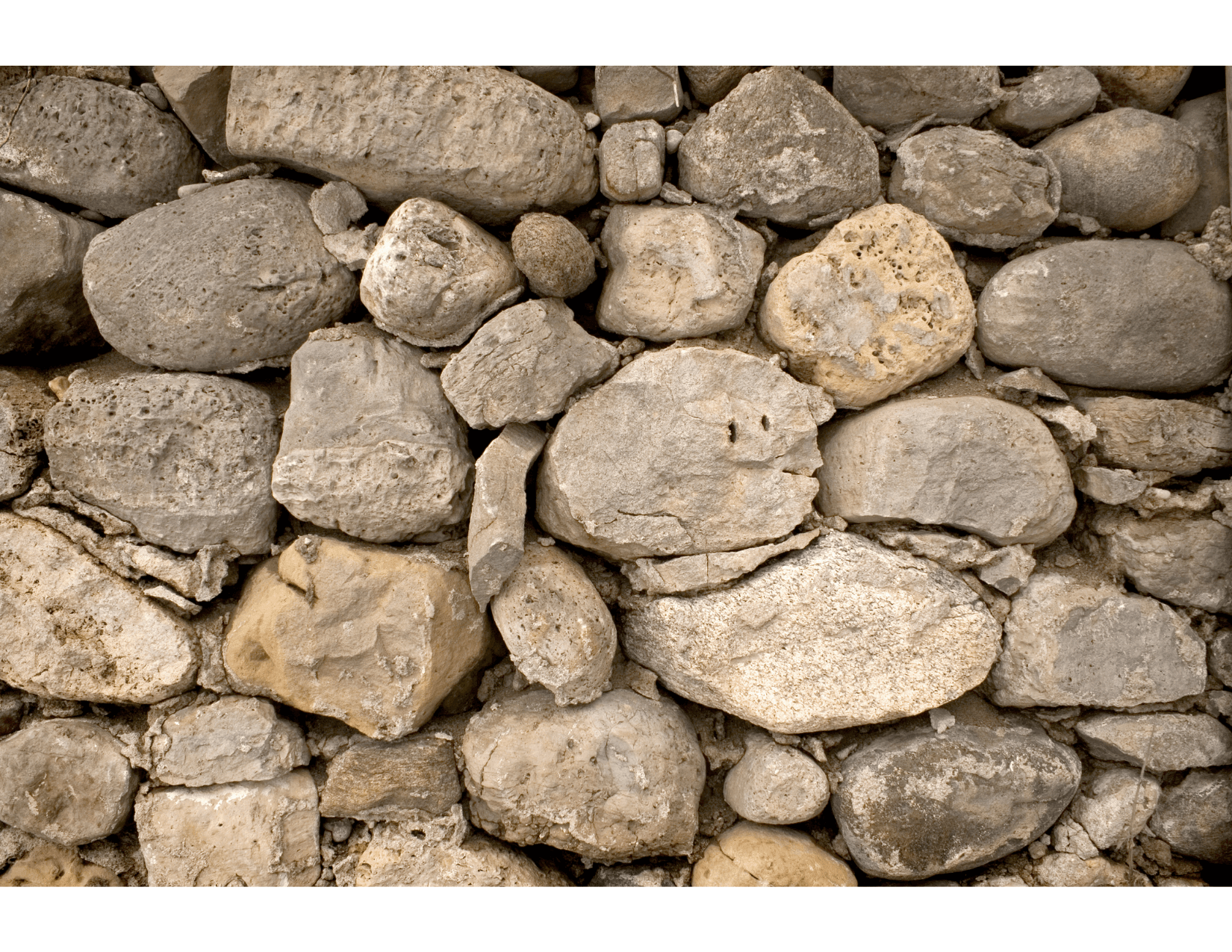 Fondations en moellons de pierre, constituées de blocs arrondis et irréguliers soigneusement assemblés, illustrant une technique traditionnelle de construction robuste et durable.