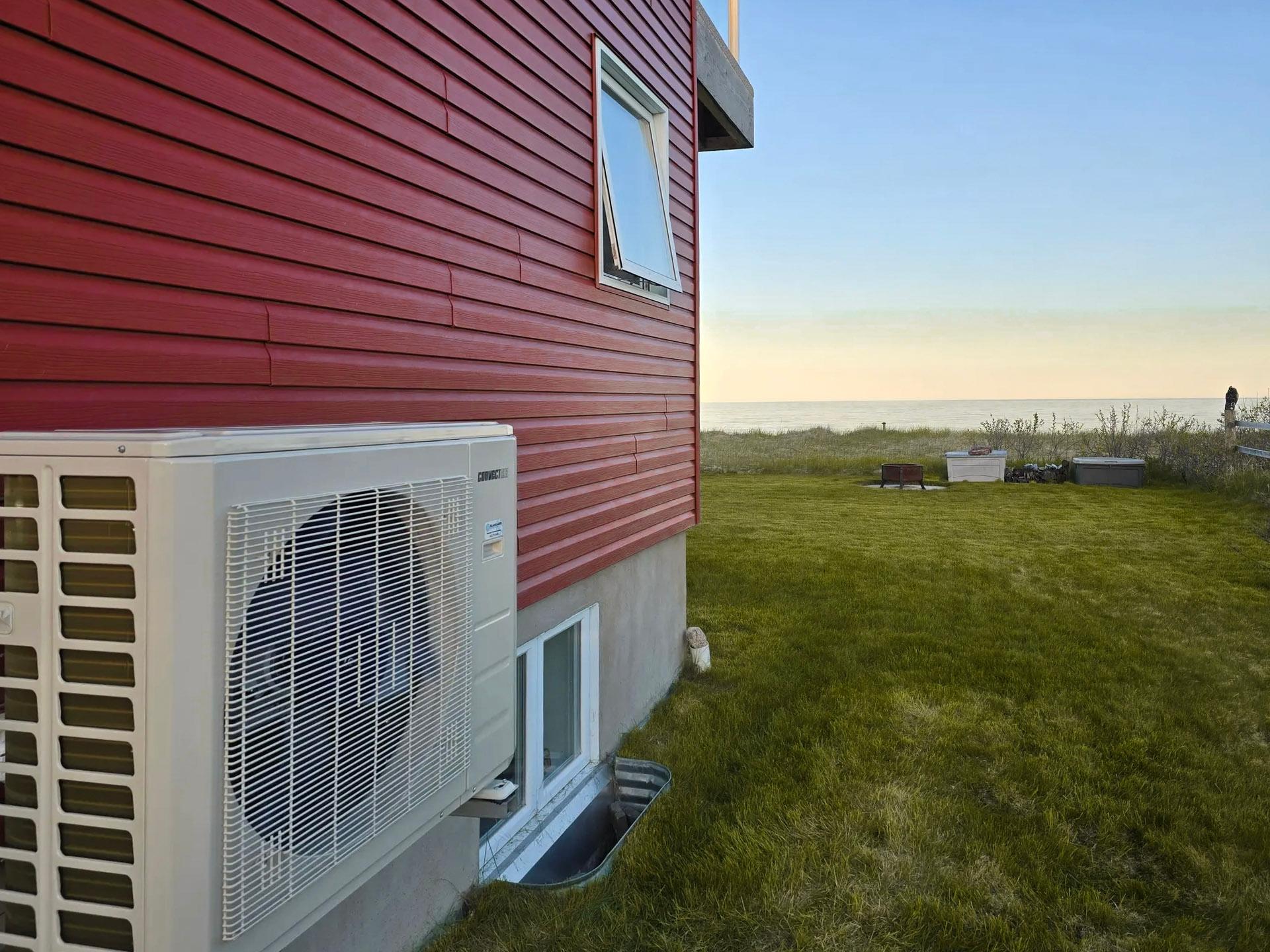 Unité de climatisation extérieure Samsung avec ventilateur, face à un jardin verdoyant et la mer