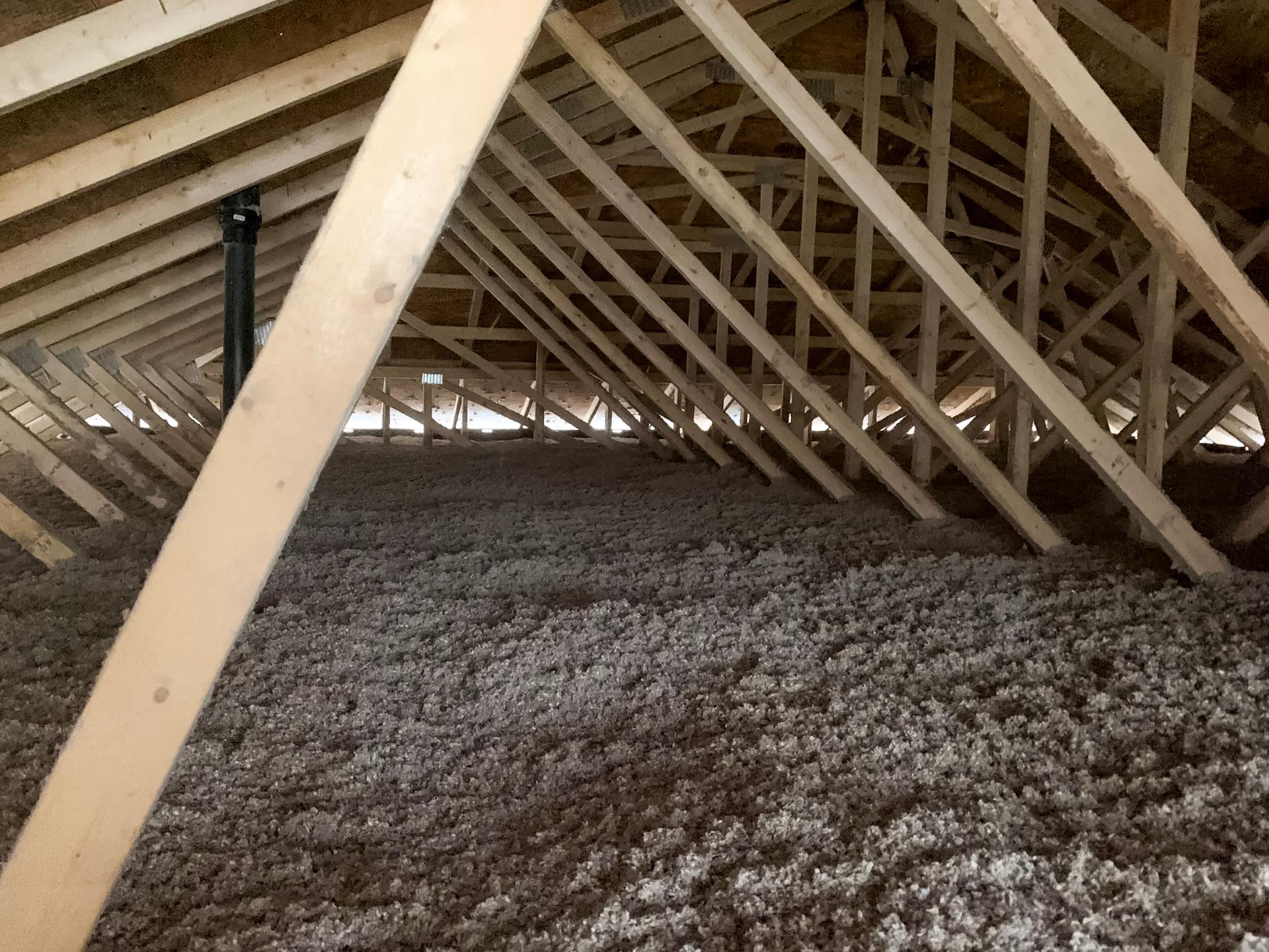 Grenier avec isolation en fibre soufflée et charpente en bois apparente.