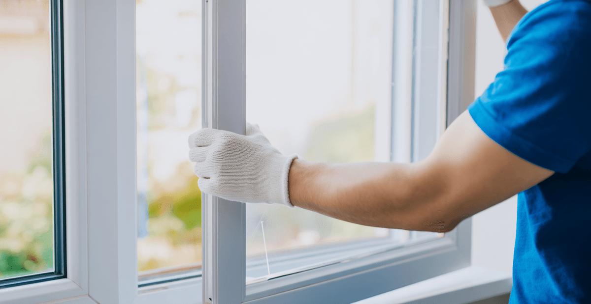 Installation d’une fenêtre en PVC par un professionnel portant des gants de protection