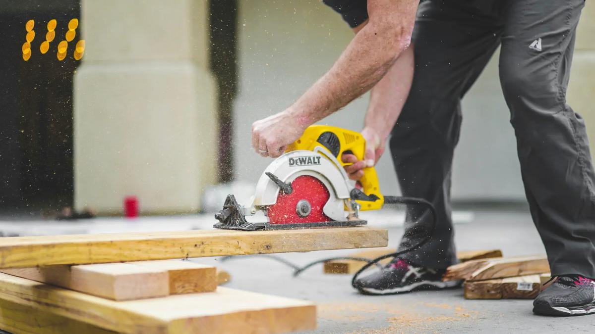 Travailleur utilisant une scie circulaire pour couper une planche de bois sur un chantier de construction