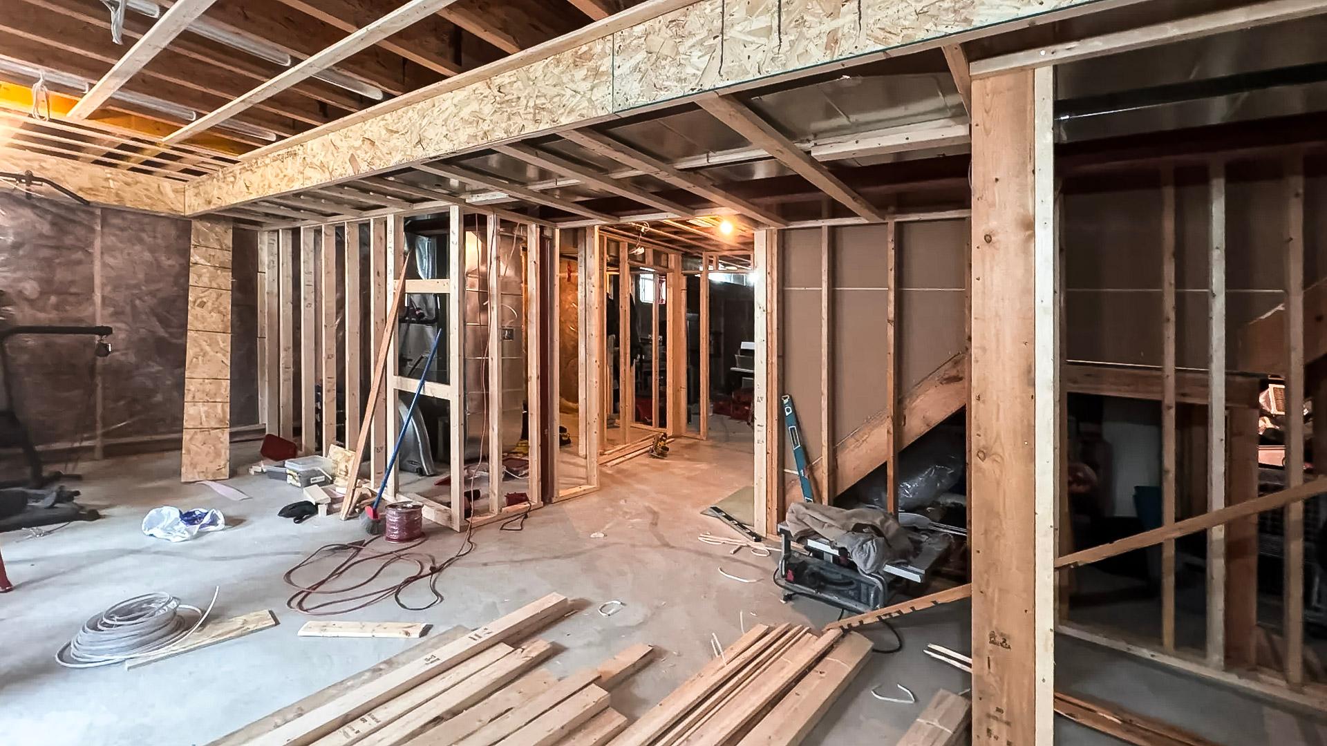 Sous-sol en rénovation avec ossature en bois, câblage électrique, et travaux de finition en cours.