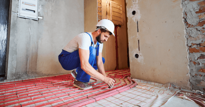 Technicien en train de poser les tuyaux d'un plancher chauffant